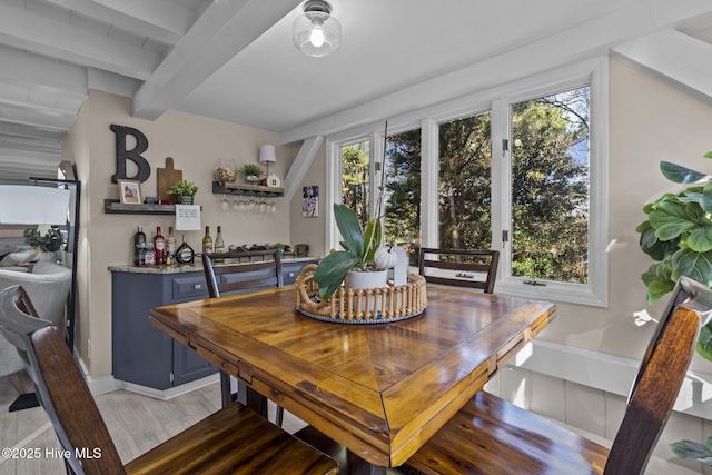 dining area with light wood-type flooring and bar area