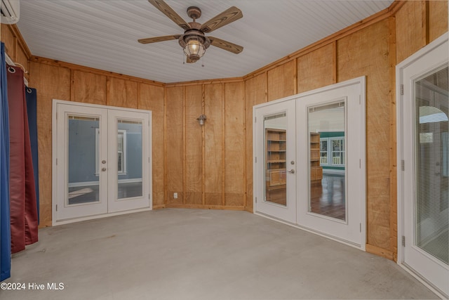 empty room with an AC wall unit, ceiling fan, and wood walls