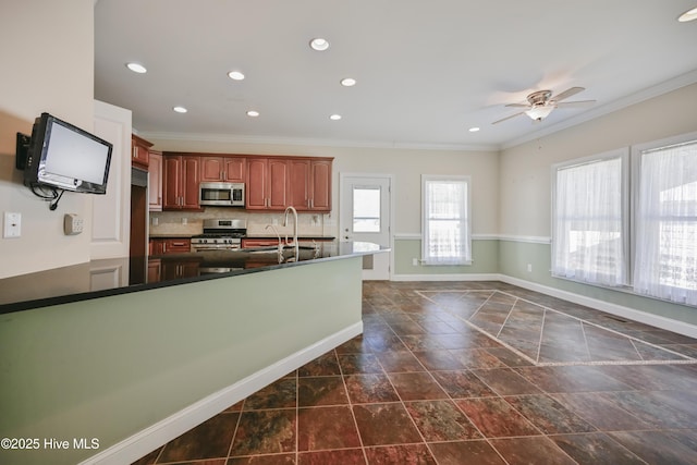 kitchen featuring tasteful backsplash, ceiling fan, ornamental molding, and an island with sink