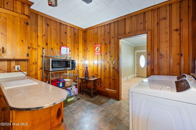 laundry room featuring separate washer and dryer, wood walls, and crown molding