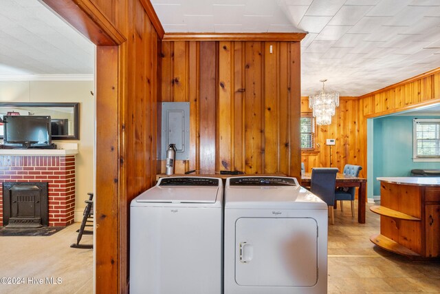 washroom featuring wooden walls, ornamental molding, a chandelier, and independent washer and dryer