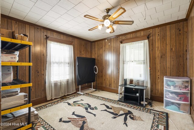 miscellaneous room with ceiling fan, wood walls, and ornamental molding