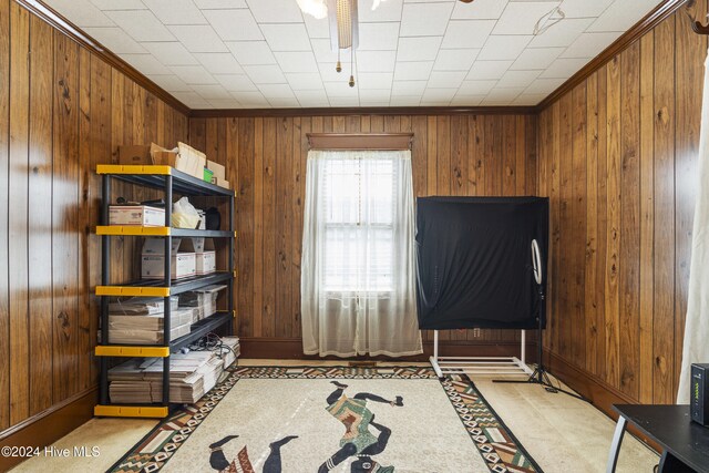 interior space featuring crown molding, ceiling fan, and wooden walls