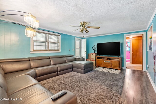 living room featuring ceiling fan with notable chandelier, a textured ceiling, hardwood / wood-style flooring, and ornamental molding