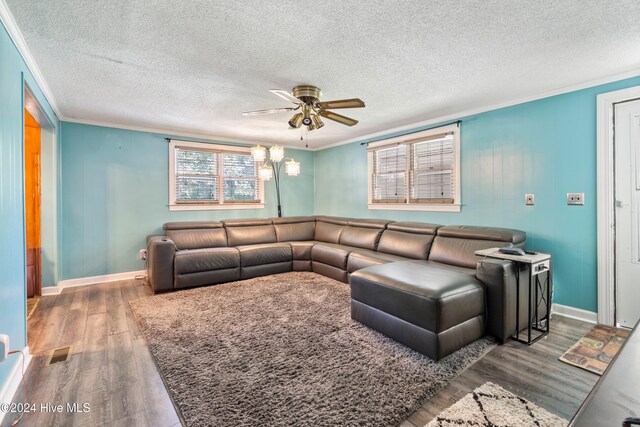 living room with a textured ceiling, hardwood / wood-style flooring, ceiling fan, and crown molding