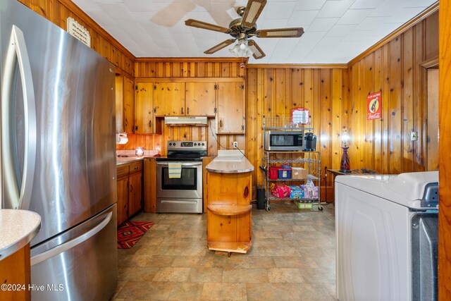 kitchen featuring ceiling fan, stainless steel appliances, washer / clothes dryer, wood walls, and crown molding