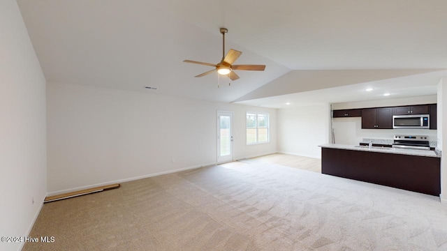 kitchen with dark brown cabinetry, stainless steel appliances, lofted ceiling, and light colored carpet