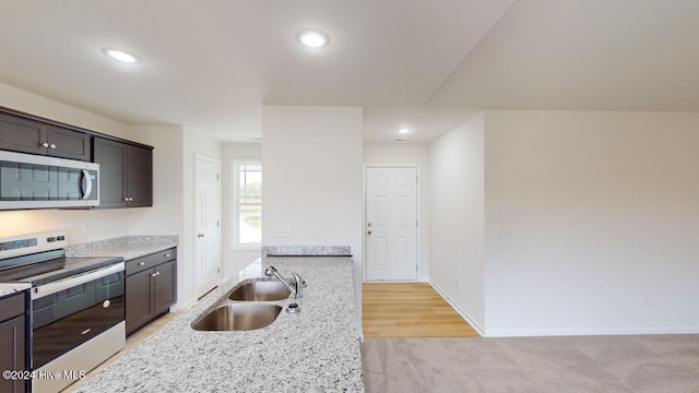 kitchen featuring light carpet, appliances with stainless steel finishes, light stone counters, dark brown cabinets, and sink