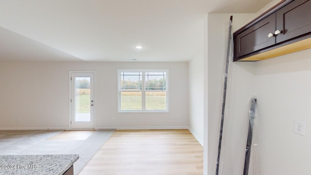 interior space featuring light stone countertops, light hardwood / wood-style floors, and dark brown cabinetry