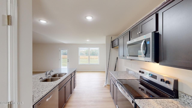 kitchen featuring light stone counters, sink, light hardwood / wood-style floors, and appliances with stainless steel finishes