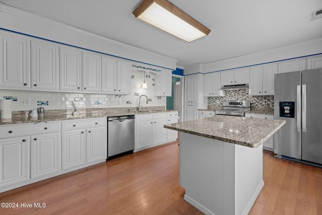 kitchen featuring appliances with stainless steel finishes, crown molding, white cabinets, a center island, and light hardwood / wood-style floors