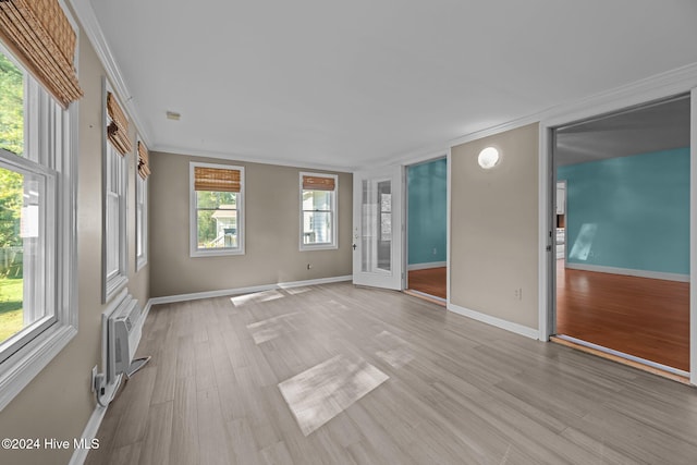 spare room featuring light hardwood / wood-style flooring, a wealth of natural light, ornamental molding, and a wall unit AC