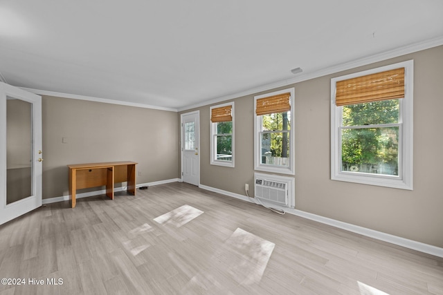 empty room with light hardwood / wood-style floors, crown molding, and a wall unit AC