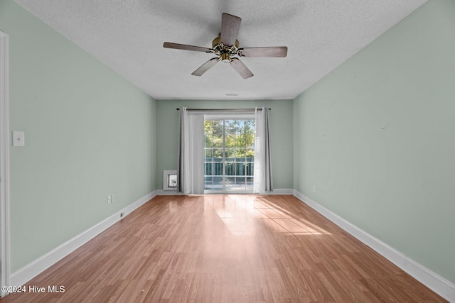 unfurnished room with ceiling fan, a textured ceiling, and light wood-type flooring