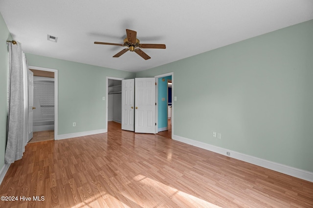 unfurnished bedroom with a closet, connected bathroom, light hardwood / wood-style floors, and ceiling fan