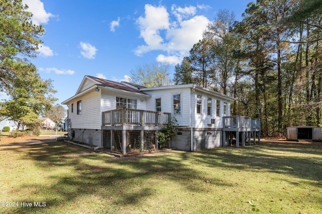 rear view of property featuring a storage unit, a lawn, and a wooden deck