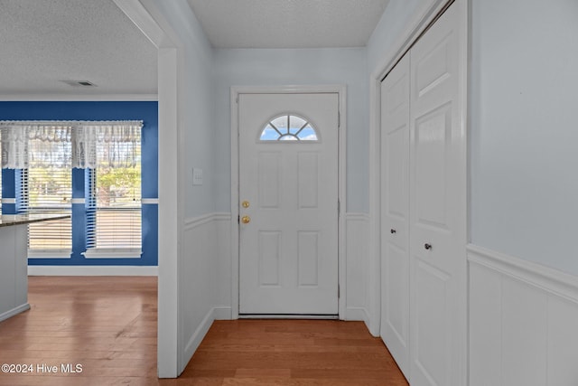 doorway to outside featuring a textured ceiling and light wood-type flooring