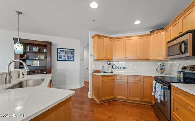 kitchen with appliances with stainless steel finishes, backsplash, sink, dark hardwood / wood-style floors, and hanging light fixtures