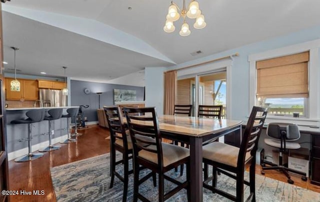 dining space with a chandelier, wood-type flooring, and vaulted ceiling