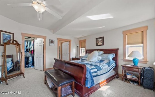 carpeted bedroom with a walk in closet, ceiling fan, and a closet