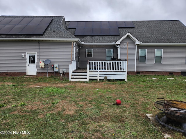 back of house featuring solar panels, a yard, and a wooden deck