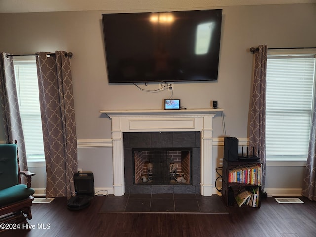 living room featuring a tile fireplace and dark wood-type flooring