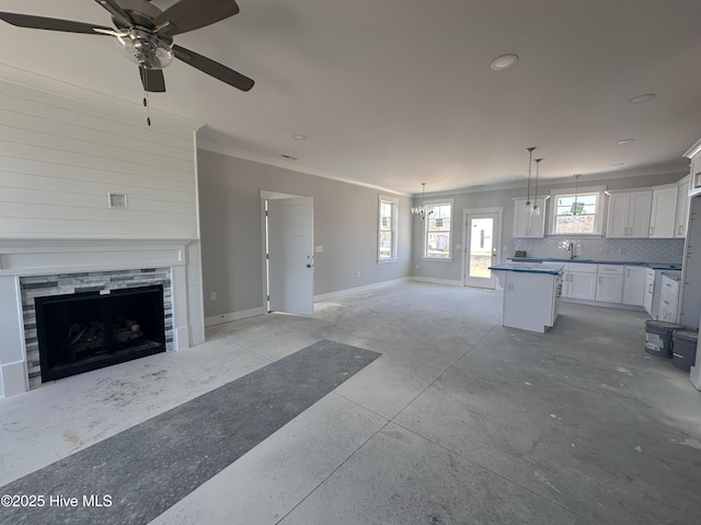 kitchen featuring open floor plan, a kitchen island, decorative backsplash, and baseboards