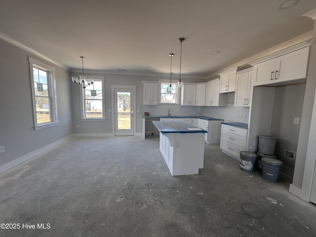 kitchen with a healthy amount of sunlight, a kitchen island, backsplash, and baseboards