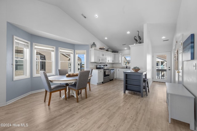 dining area featuring light wood-type flooring, high vaulted ceiling, and sink