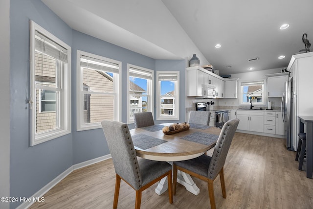 dining space with lofted ceiling, light wood-type flooring, and sink