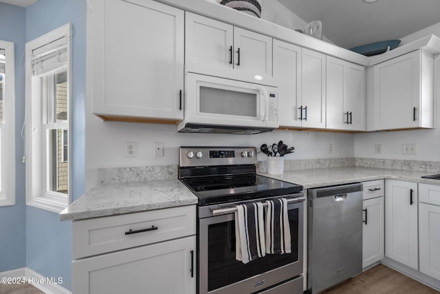 kitchen featuring light hardwood / wood-style floors, white cabinetry, light stone countertops, and appliances with stainless steel finishes