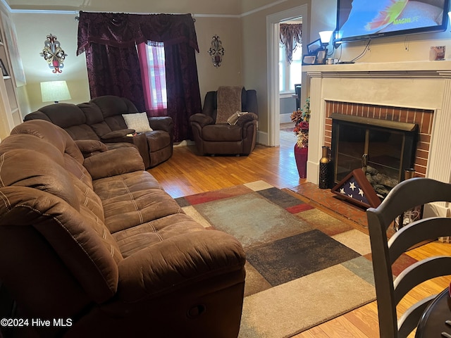 living room featuring crown molding, hardwood / wood-style floors, and a brick fireplace