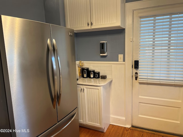 kitchen featuring white cabinets, stainless steel fridge, and wood-type flooring