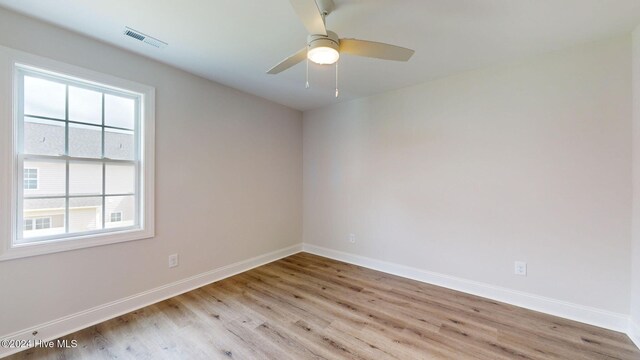 spare room featuring ceiling fan, light wood-type flooring, visible vents, and baseboards