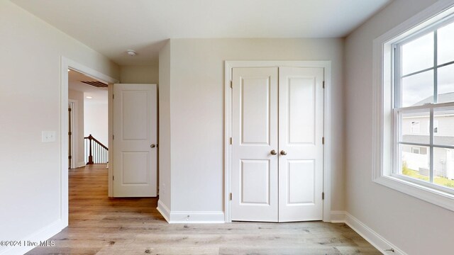 unfurnished bedroom with light wood-style flooring, visible vents, baseboards, and a closet