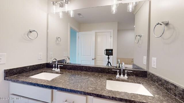 full bathroom with visible vents, a sink, and double vanity