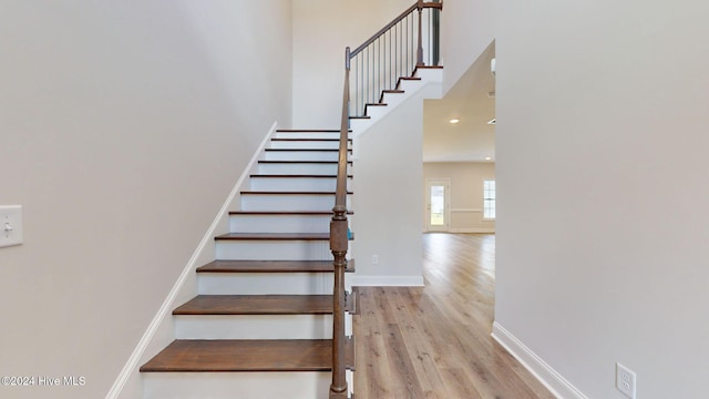 stairs with a high ceiling, baseboards, and wood finished floors