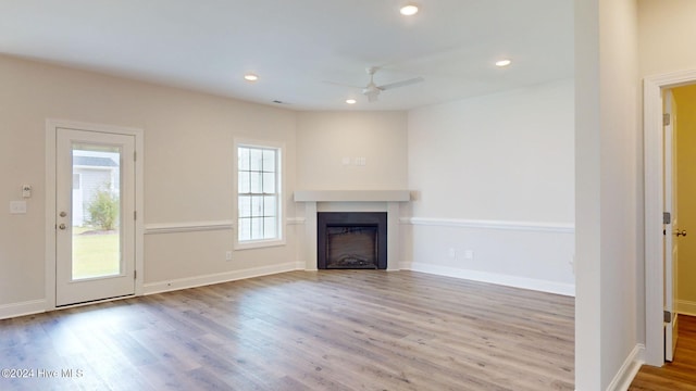 unfurnished living room featuring baseboards, a fireplace, wood finished floors, and recessed lighting