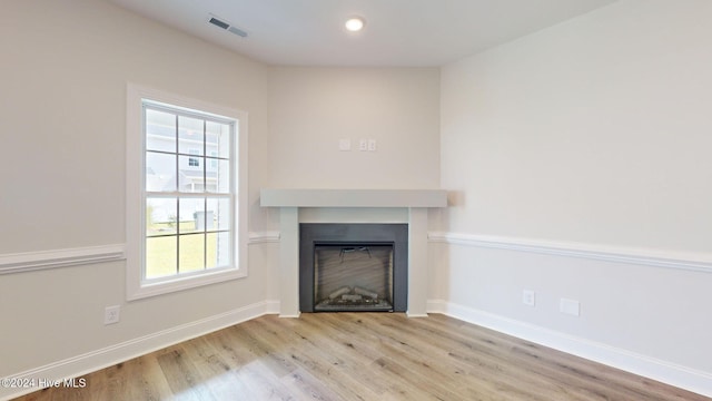 unfurnished living room with visible vents, a fireplace, baseboards, and wood finished floors