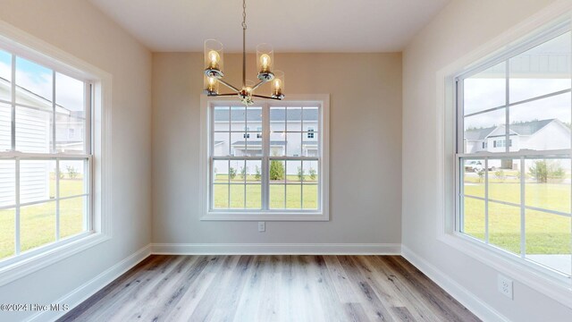 unfurnished dining area with baseboards, light wood-style floors, and a notable chandelier