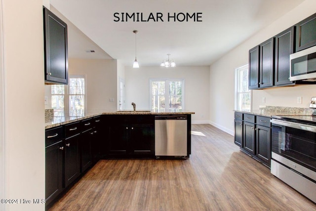 kitchen featuring pendant lighting, light stone counters, hardwood / wood-style floors, and stainless steel appliances