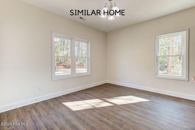 empty room featuring dark hardwood / wood-style flooring and a chandelier