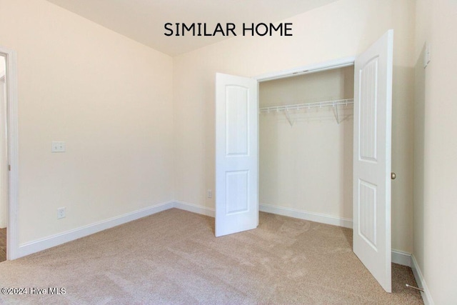 unfurnished bedroom featuring a closet and light colored carpet