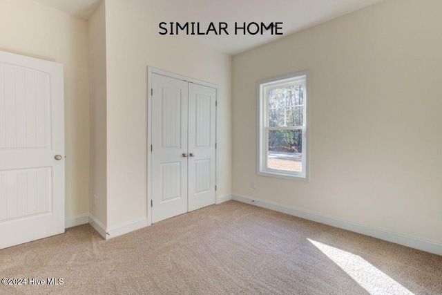 unfurnished bedroom with light carpet and a closet