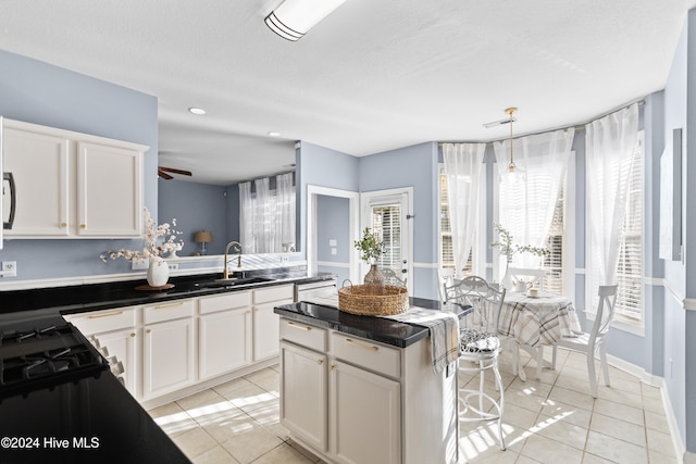 kitchen with white cabinets, decorative light fixtures, a kitchen island, and sink