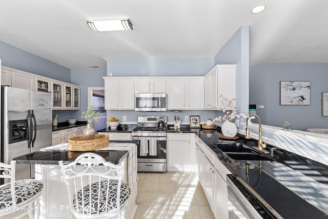 kitchen with white cabinetry, sink, a breakfast bar, light tile patterned floors, and appliances with stainless steel finishes