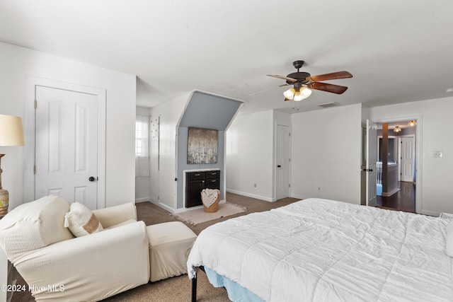 bedroom featuring ceiling fan, dark carpet, and ensuite bathroom