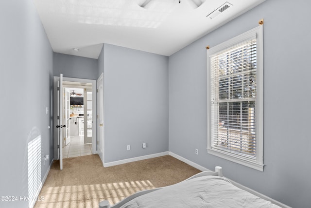 carpeted bedroom with ceiling fan and multiple windows