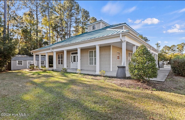 view of front facade with covered porch, a front lawn, and a storage shed