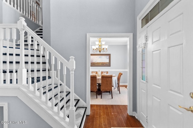 staircase with hardwood / wood-style flooring and a notable chandelier